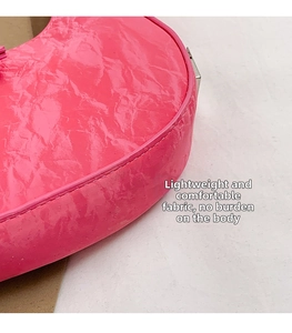 Macro shot of hot pink crescent bag featuring pleated texture and precise bottom stitching