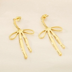 Macro detail of 18K gold bow earrings featuring sparkling white rhinestone accents