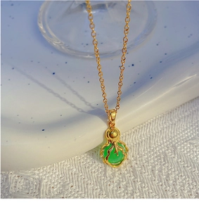Macro d'un collier doré avec pendentif chou chinois vert et une fine chaîne à maillons