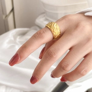 Macro detail of wide irregular lava texture gold ring with a modern embossed surface