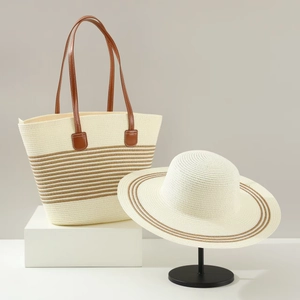 Detailed close-up of straw tote bag and matching wide-brim sun hat with brown stripes