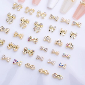 Close-up of golden alloy bow nail charms with pearls and rhinestones for DIY nail art designs