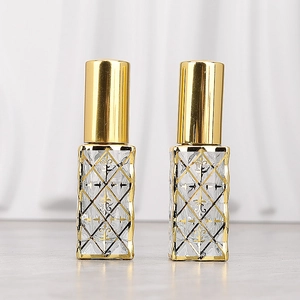Macro detail of diamond pattern on two clear glass perfume bottles with gold caps