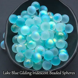 12mm iridescent blue glass beads with gold foil and matte finish in a black ceramic tray