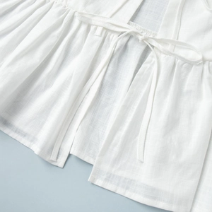 Detailed view of white cotton fabric with grid texture and ruffle lace-up closures