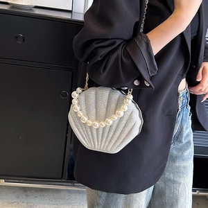 Silver glitter shell handbag with pearl handle and golden chain strap shown by a model