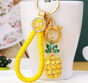 Detailed close-up of pineapple keychain with yellow opal beads and gold braided rope