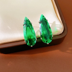 Detail of green teardrop zircon earrings with silver prong setting in a luxury jewelry box