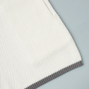 Detailed macro shot of white knit texture with grey ribbed hem finish on vest