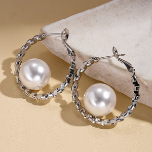 Silver chain hoop earrings with large white pearls on a natural stone background