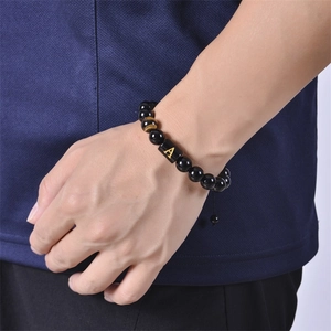 Detailed shot of an adjustable black onyx bead bracelet with a golden letter A charm