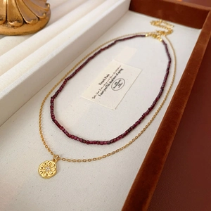 Détail du collier double rang en perles de grenat bordeaux et pendentif lune doré
