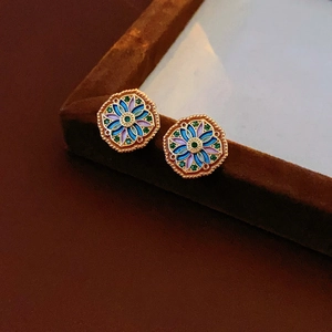 Macro shot of vintage gold flower earrings with colorful enamel and inlaid gemstones