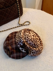Detail van stoffen hoeden met luipaardprint en ruitjes met strikken op wit pluche