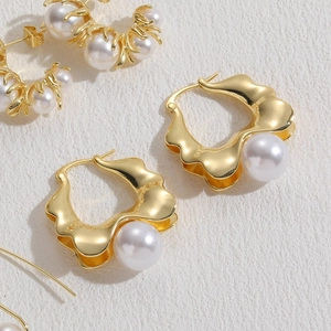 Macro shot of 14K gold plated geometric wave earrings with round white pearls