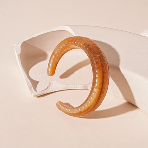 Detail of amber acrylic cuff bracelet with ribbed texture and glossy finish