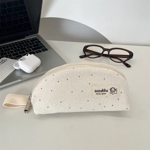 Detail of soft wool polka dot pencil case with sturdy metal zipper and woven handle