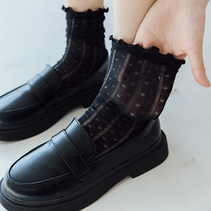 Black sheer crew socks with polka dots and ruffle cuffs worn with loafers