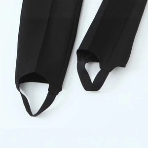 Close-up of black stirrup leggings with elastic foot straps on a white background