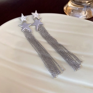Detailed shot of silver star fringe earrings with tassel chains on ceramic plate