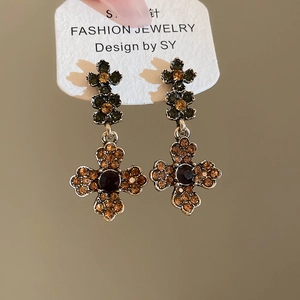 Detail of vintage baroque crystal earrings with green flower and amber cross drops