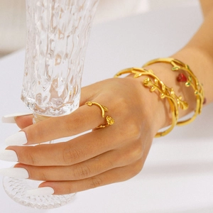 Gold plated rose vine ring and bracelet set worn by a model holding a crystal glass