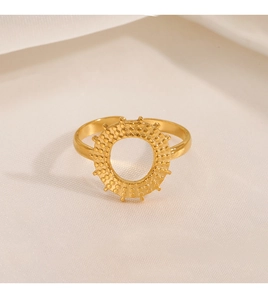 Macro shot of gold stainless steel ring featuring granular texture and cutout sunburst design