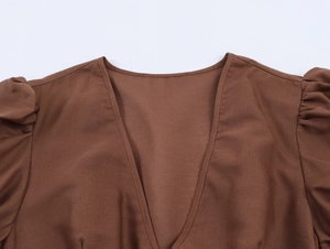Détail de l'élégant décolleté en V marron et des manches bouffantes plissées sur cette robe