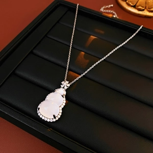 Detailed close-up of a zircon gourd pendant on a silver necklace over a black display tray