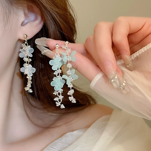 Detail view of long flower tassel earrings with crystals in white and mint green