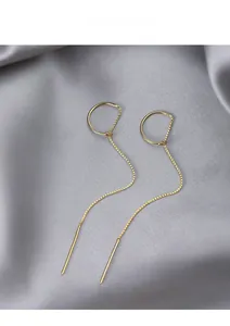 Detail of minimalist gold-plated threader earrings with sleek circular drop on grey velvet