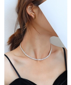 Detail of luxury full zircon choker and gold curved earrings worn by a model