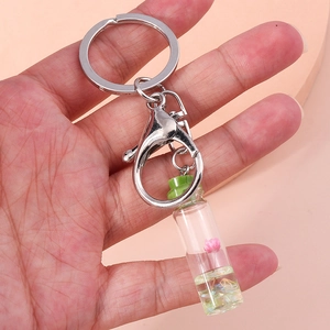 Close-up of a fruit wishing bottle keychain with a pink flower inside on a soft background