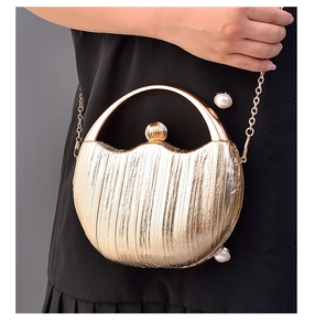Detailed shot of golden semicircular evening bag with vertical texture and pearl clasp