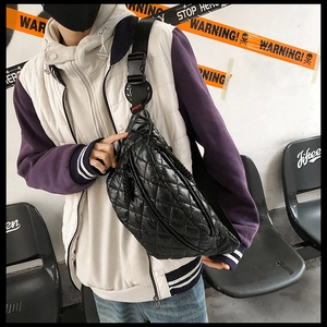 Close-up of black quilted waist bag with adjustable strap in street style setting