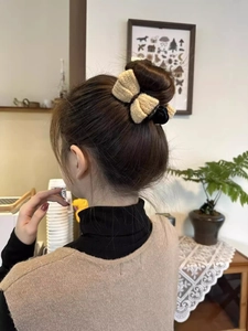 Beige knitted bow hair claw clip styled on a low bun hair for a cozy winter look