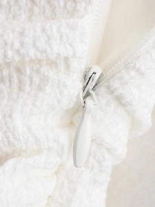 Detail of white textured fabric with high-quality invisible zipper and bubbled texture