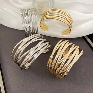 Detailed view of layered hollow crossover metal bangles in polished gold and silver finish