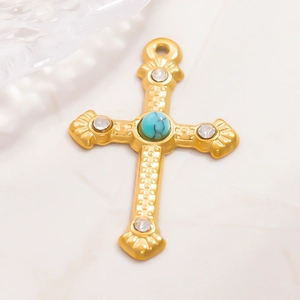 Dettaglio macro del ciondolo a croce in oro 18K con perla turchese e cristalli