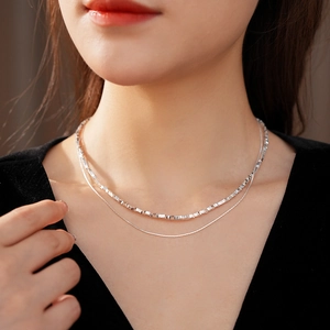 Close-up of double layer silver chain necklace on neck with square and snake links