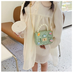 Detail of green quilted girls' crossbody bag with pearl handle and golden chain strap