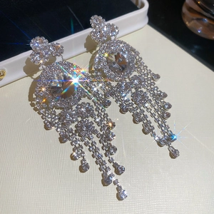 Detailed close-up of silver geometric tassel earrings with sparkling rhinestones on jewelry box
