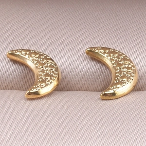 Macro view of golden crescent moon earrings with textured dot pattern in a pink jewelry box