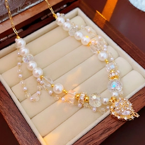 Macro detail of a double-layer necklace with pearls, crystals, and a heart pendant