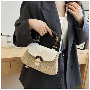Detail of woven straw handbag featuring bamboo handle and pleated white faux leather flap