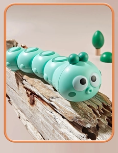 Detailed view of green wind-up caterpillar toy on textured wood with forest background