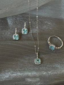 Macro view of blue cushion-cut gemstone jewelry set with halo diamond accents