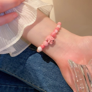 Detailed view of pink beaded bracelet with a cute ceramic elephant charm on a female wrist