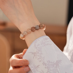 Macro detail of natural red rutilated quartz beaded bracelet on a woman's wrist