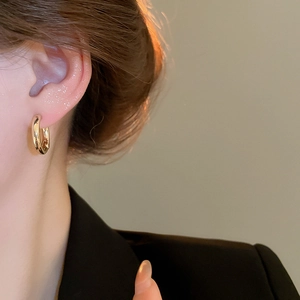 Close-up of elegant gold hoop earrings with a polished finish worn by a model